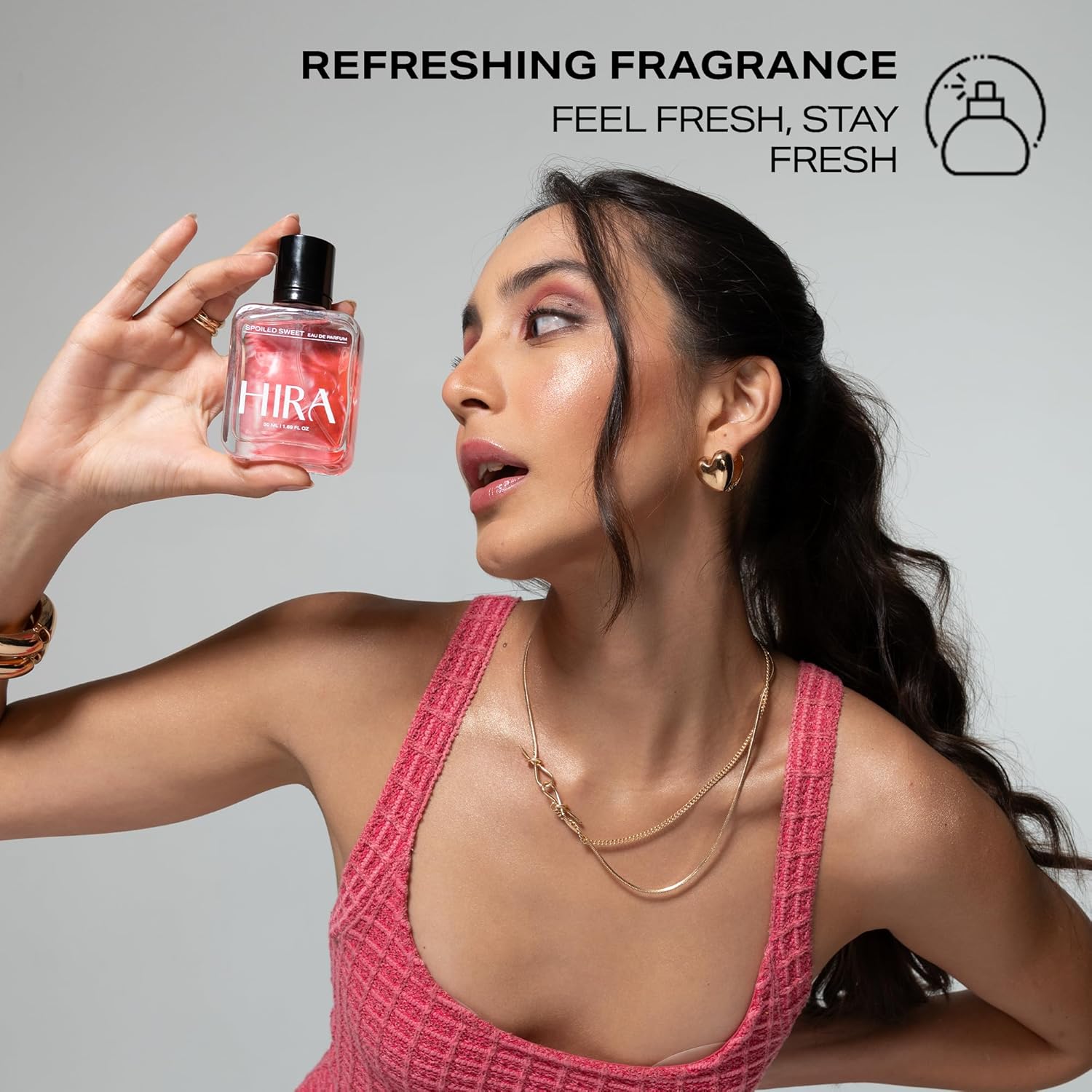 Woman holding a pink HIRA perfume bottle with 'Refreshing Fragrance' text above.