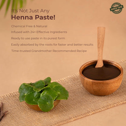 Henna paste in a wooden bowl with a wooden spoon, surrounded by henna leaves on a beige background.