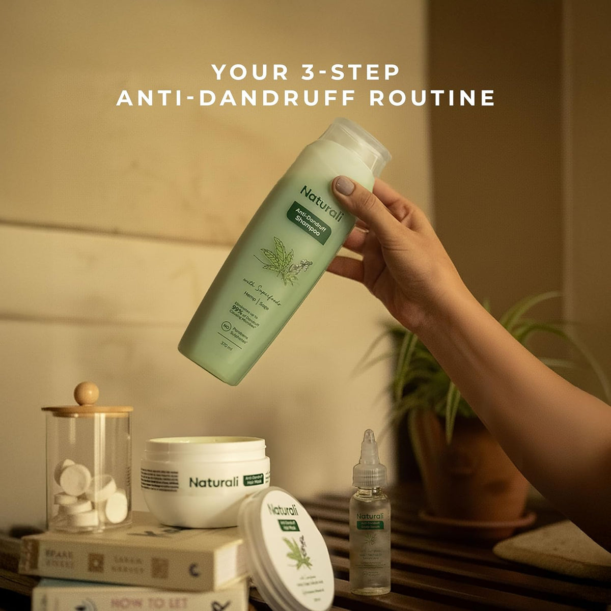 Hand holding a bottle of Naturalii shampoo with anti-dandruff products on a wooden surface.