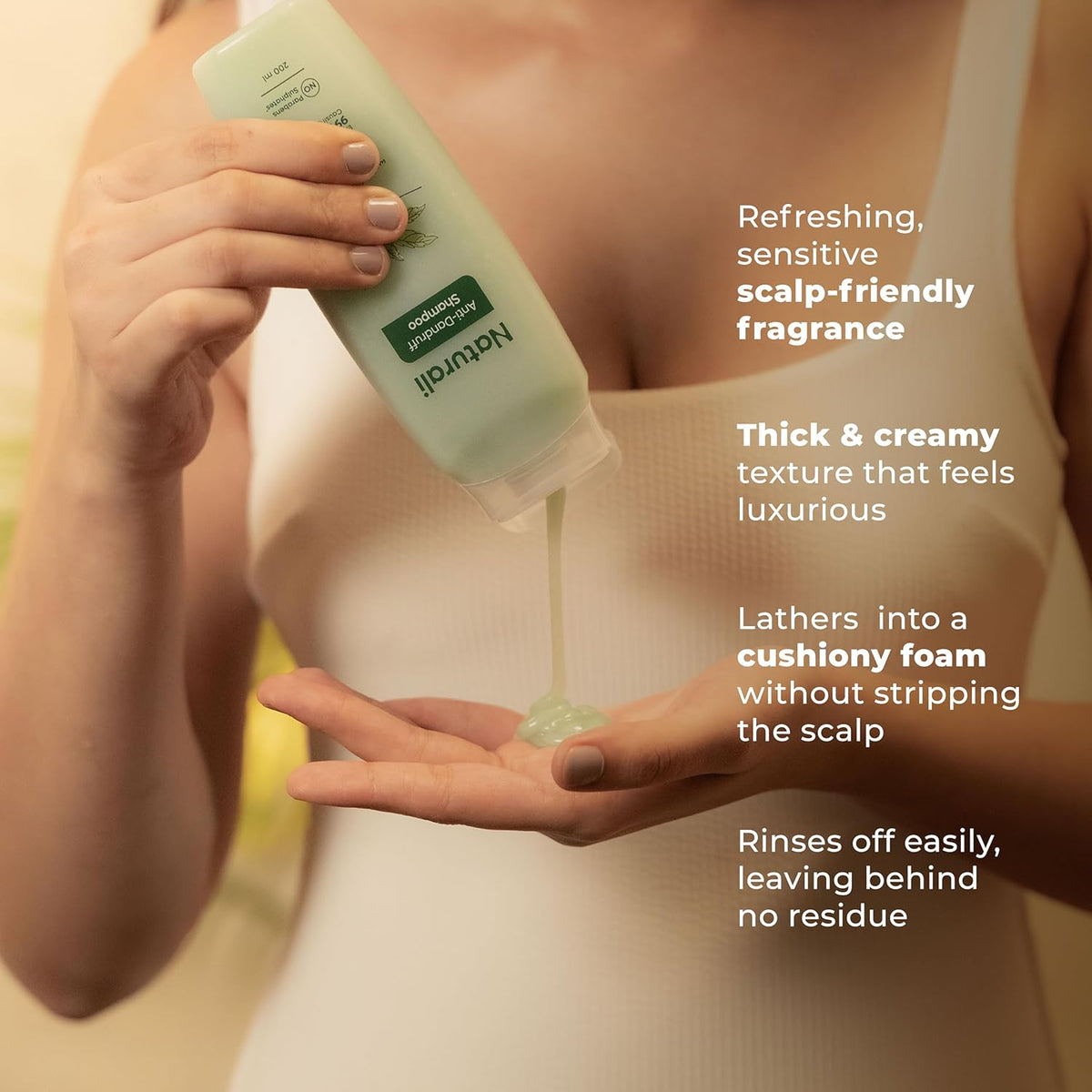 Person holding a bottle of Natura Siberica shampoo with product being poured into hands, featuring product benefits text.