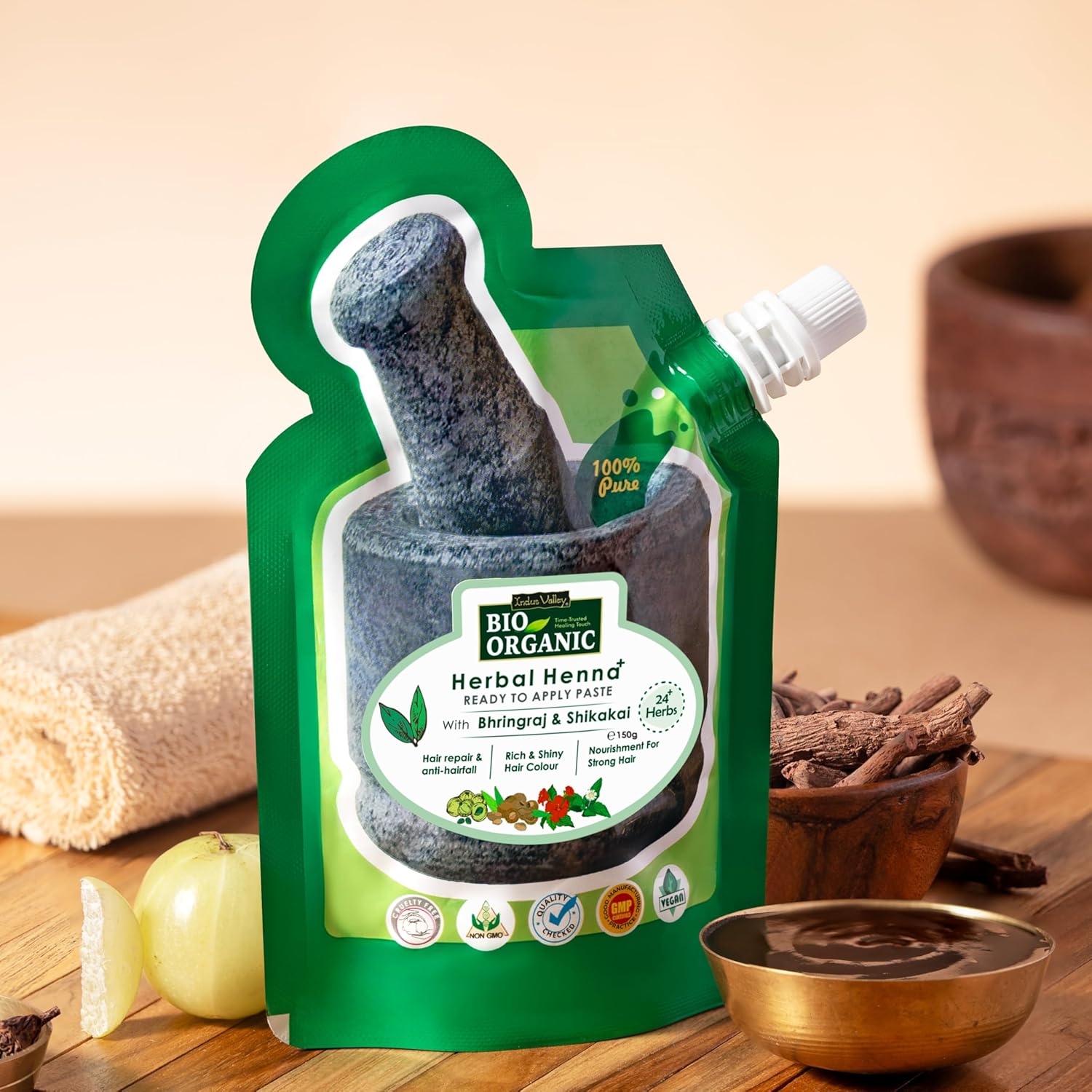 Green packaging of Bio Organic Herbal Henna on a wooden surface with ingredients.