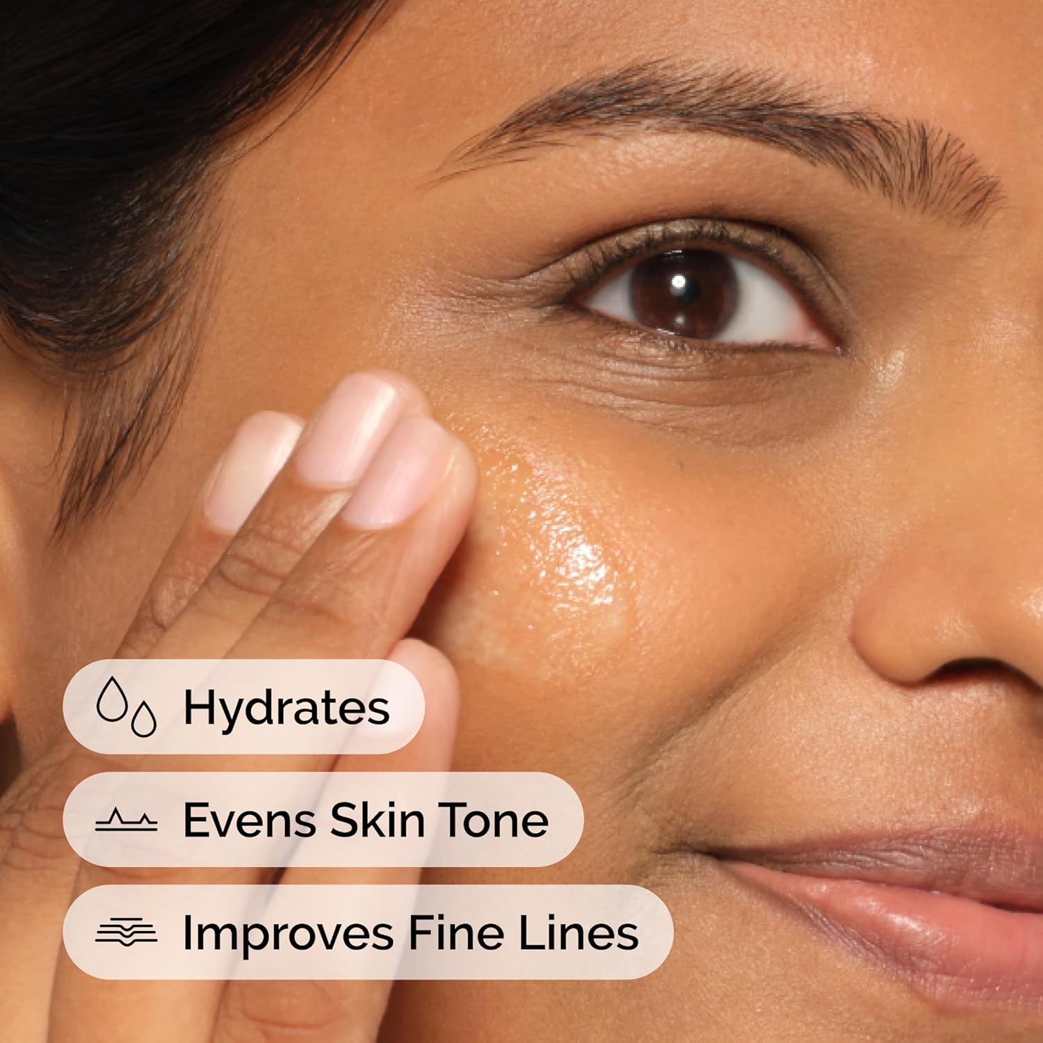 Woman applying skincare product to her face with text indicating hydration, skin tone evening, and line improvement.