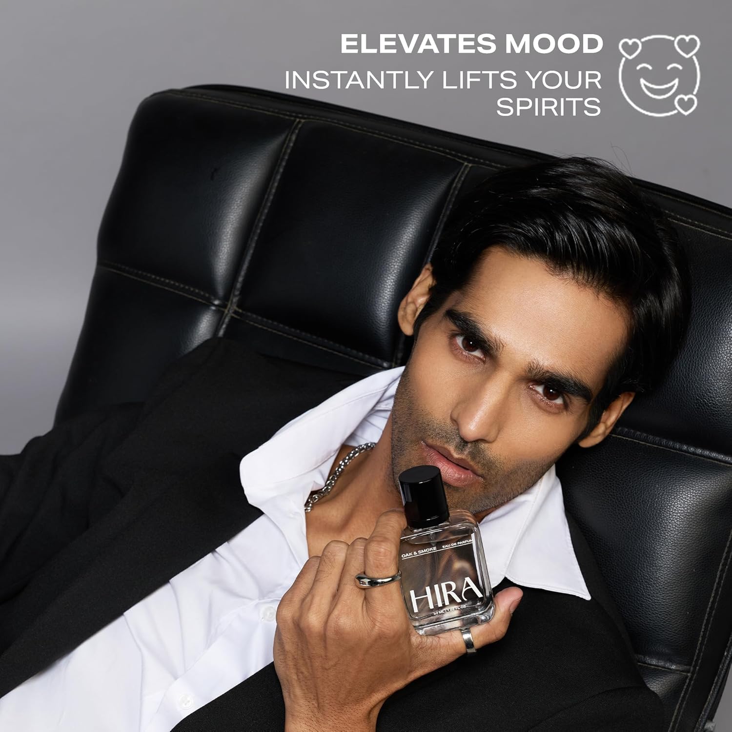 Man holding a bottle of Hira perfume with promotional text on a gray background