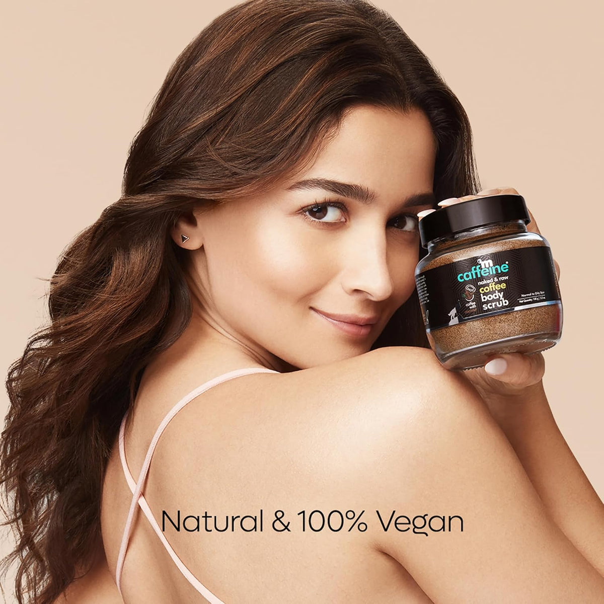 Woman holding a jar of Caffeine Free Body Scrub with a beige background