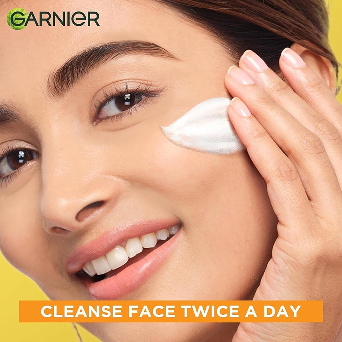 Woman applying cream to her face with Garnier logo and text about face cleansing.