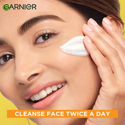 Woman applying cream to her face with Garnier logo and text about face cleansing.
