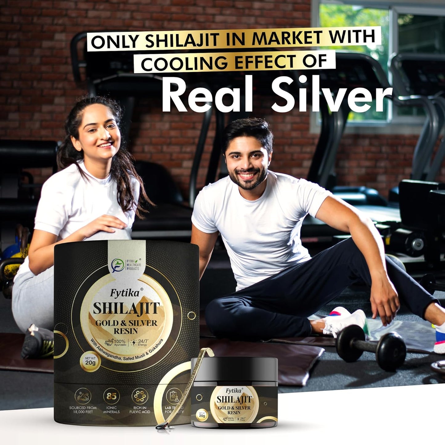 Two people sitting on a gym floor with Fytika Shilajit Gold & Silver Resin packaging in front of them.