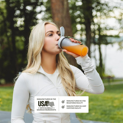 Woman drinking from a reusable water bottle outdoors with a label about manufacturing in the USA.