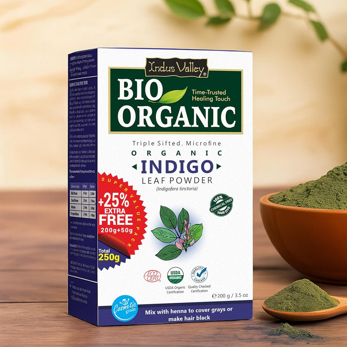 Box of Indus Valley Bio Organic Indigo Leaf Powder with a bowl and spoon of powder on a wooden surface.