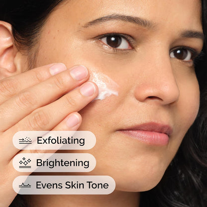 Woman applying cream to her face with text indicating exfoliating, brightening, and even skin tone benefits.
