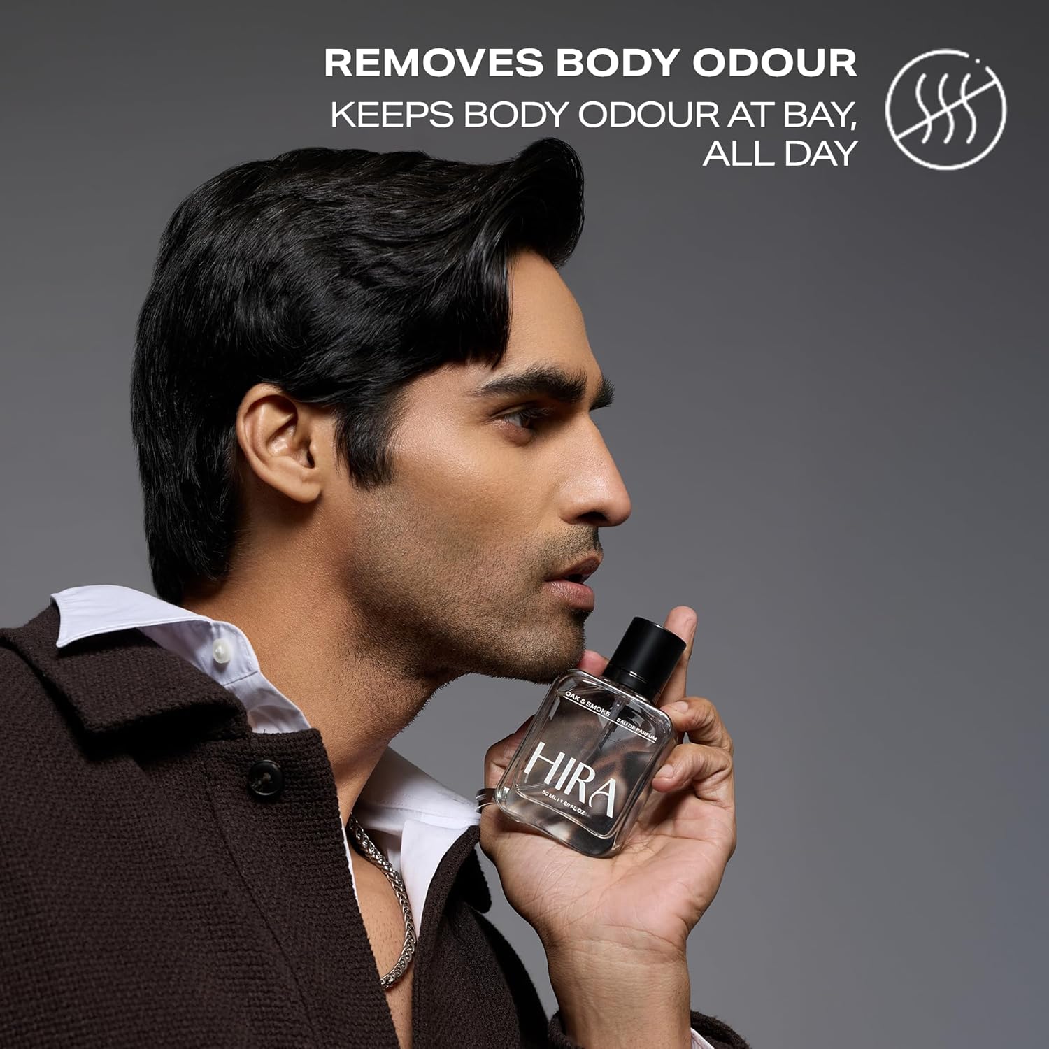 Man holding a HIRA perfume bottle with text about odor removal on a gray background