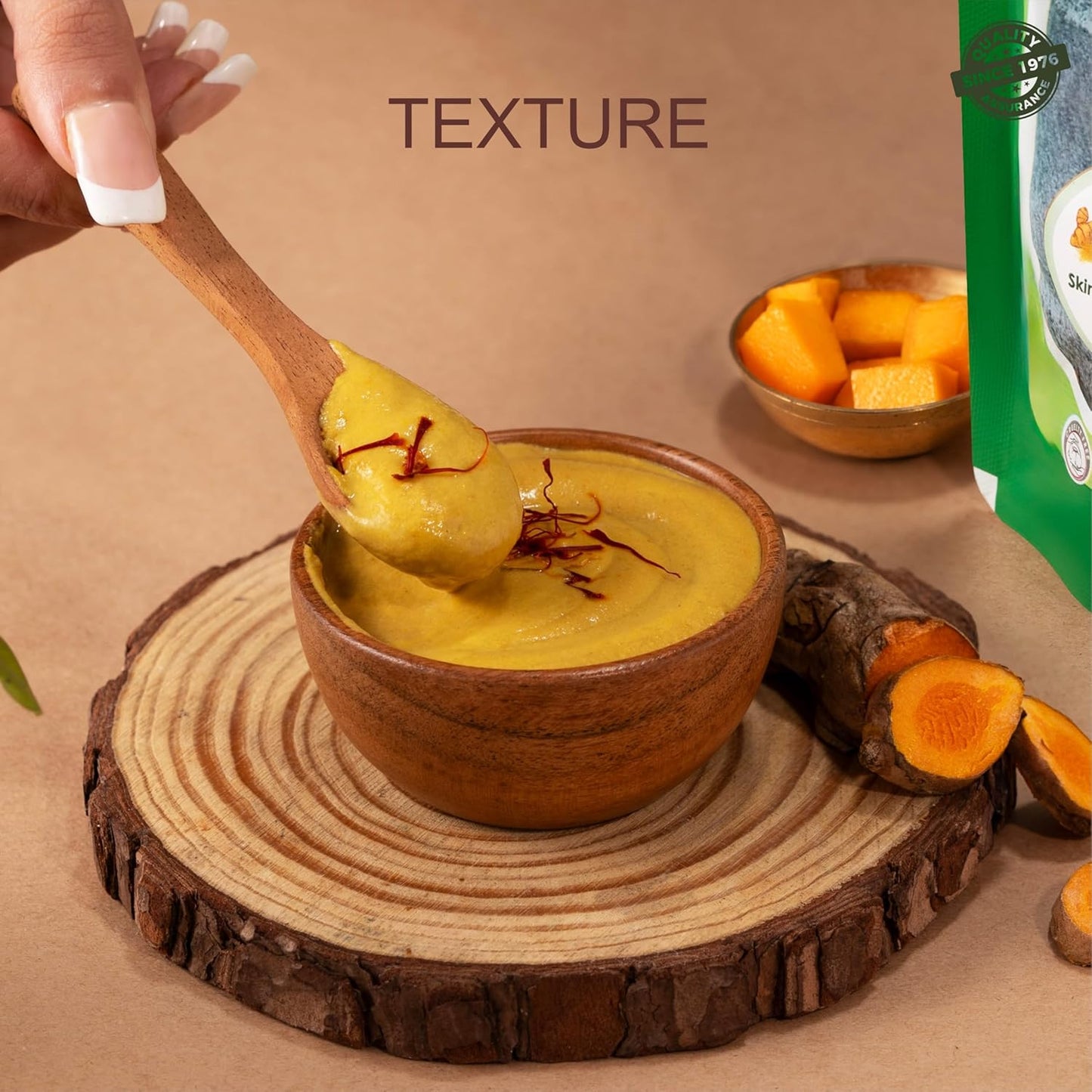Spoonful of yellow dessert with saffron over a wooden bowl on a rustic wooden surface.