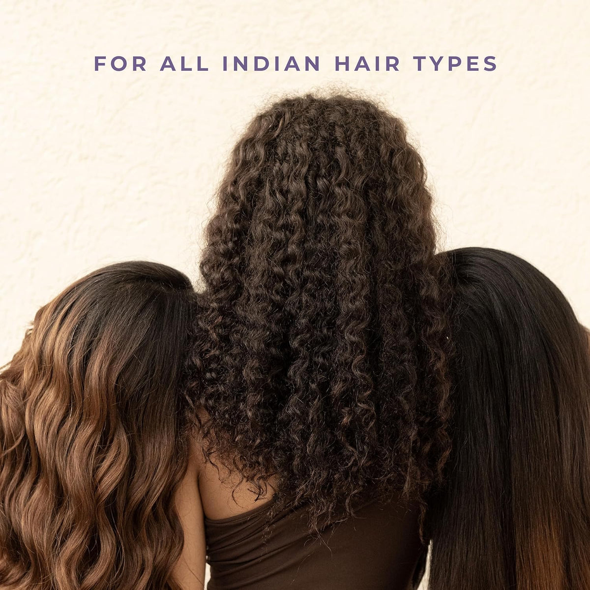 Three women with different hair types standing close together against a beige background.
