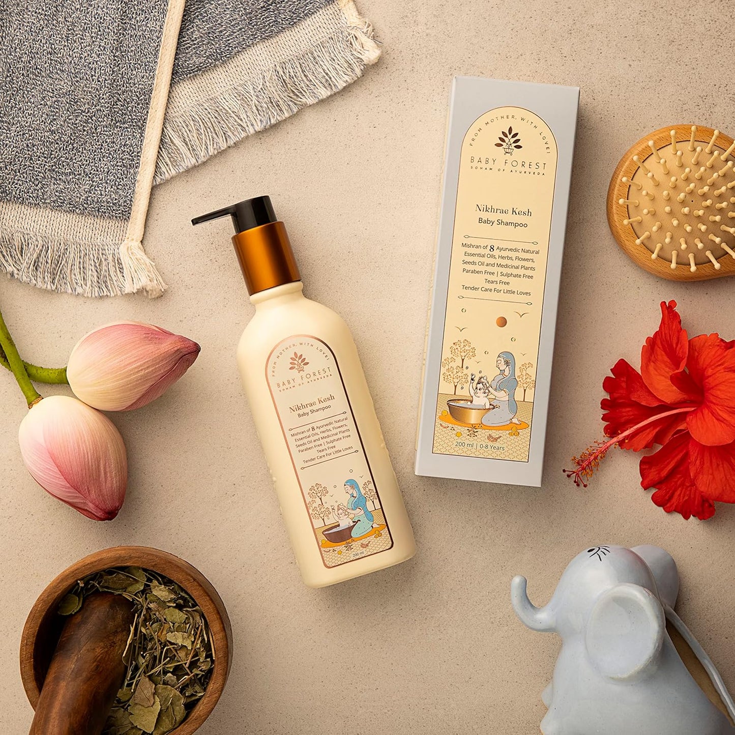 Baby shampoo bottle with packaging, flowers, and a mortar on a beige surface