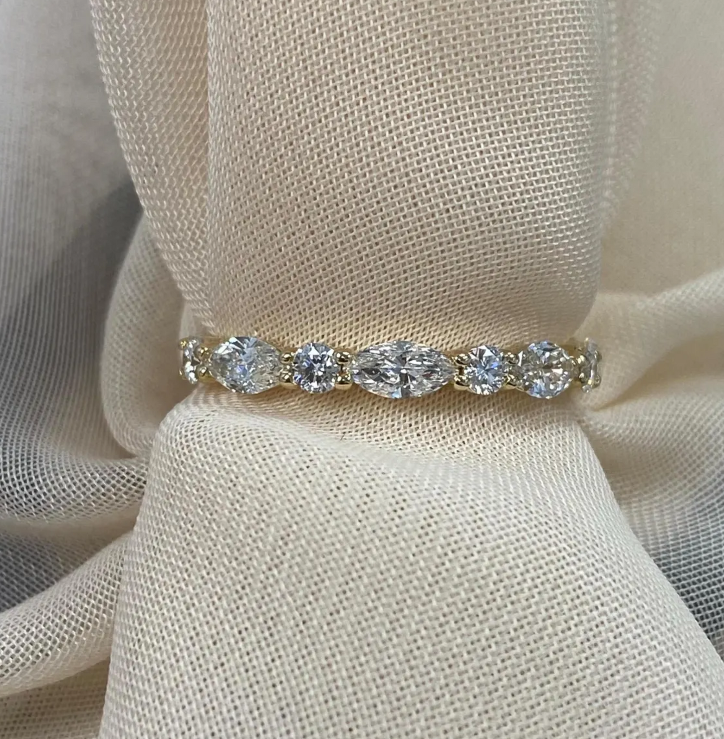 Gold ring with diamonds on a beige fabric background