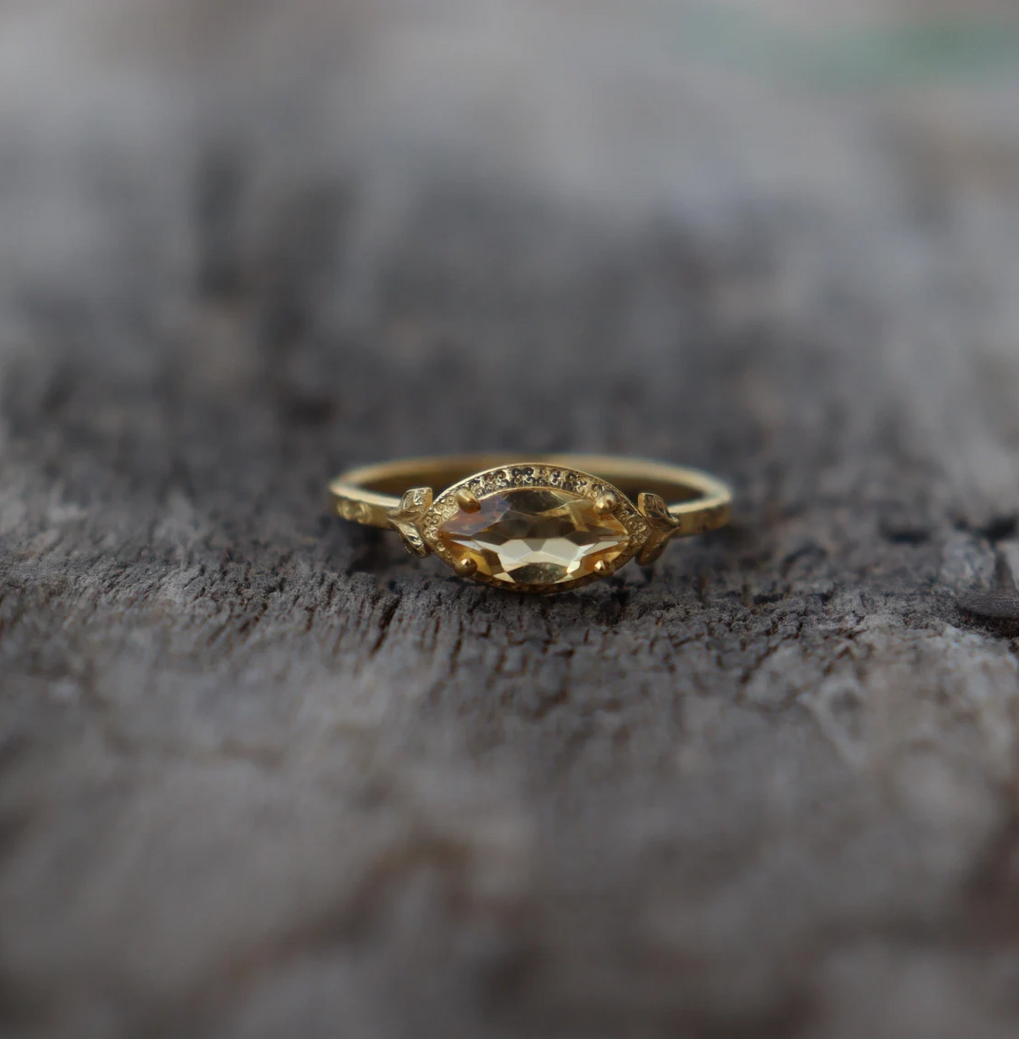 Gold ring with a yellow gemstone on a textured surface