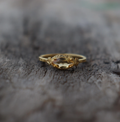 Gold ring with a yellow gemstone on a textured surface