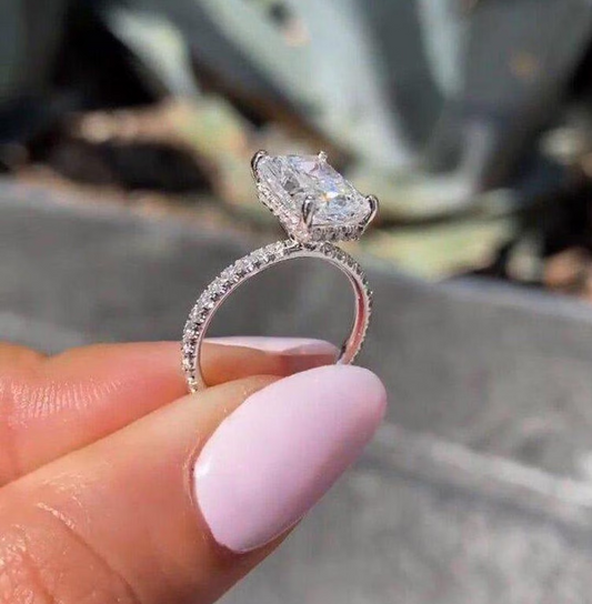 Diamond ring held between fingers with a natural background