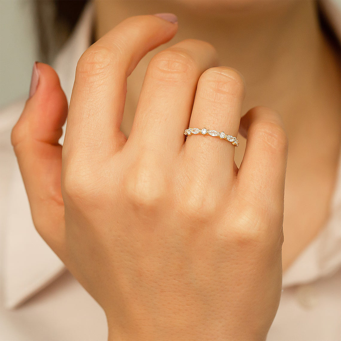 Hand wearing a diamond ring with a soft focus background
