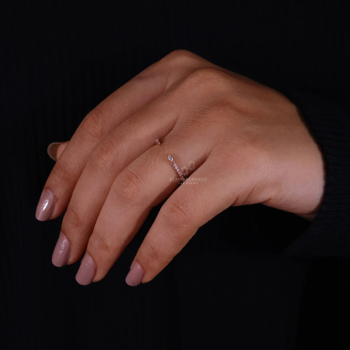 Hand wearing a ring with a clear gemstone on a black background