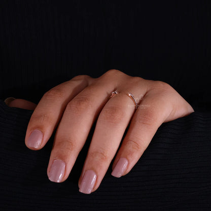 Hand with pink nail polish wearing a ring on a black background