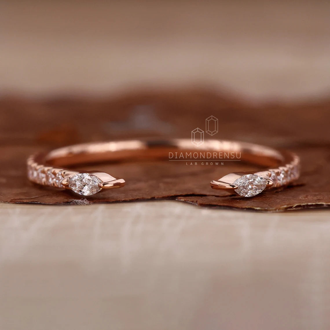 Rose gold ring with diamond accents on a textured surface, featuring the brand 'Diamondrensu'.