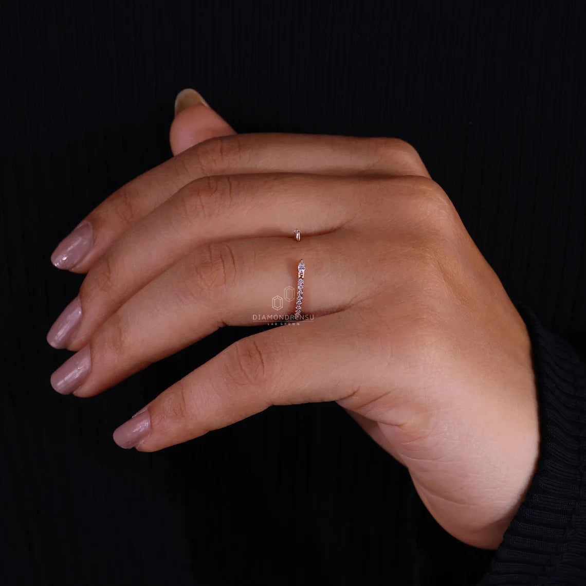 Hand wearing a thin ring on a black background