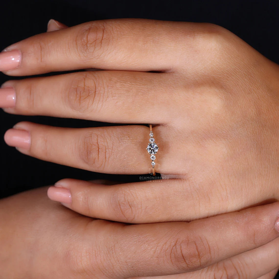 Close-up of a hand wearing a diamond ring on a black background
