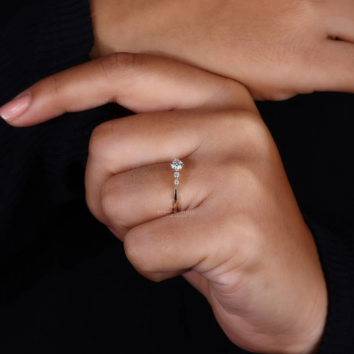 Close-up of a hand wearing a diamond ring on a black background