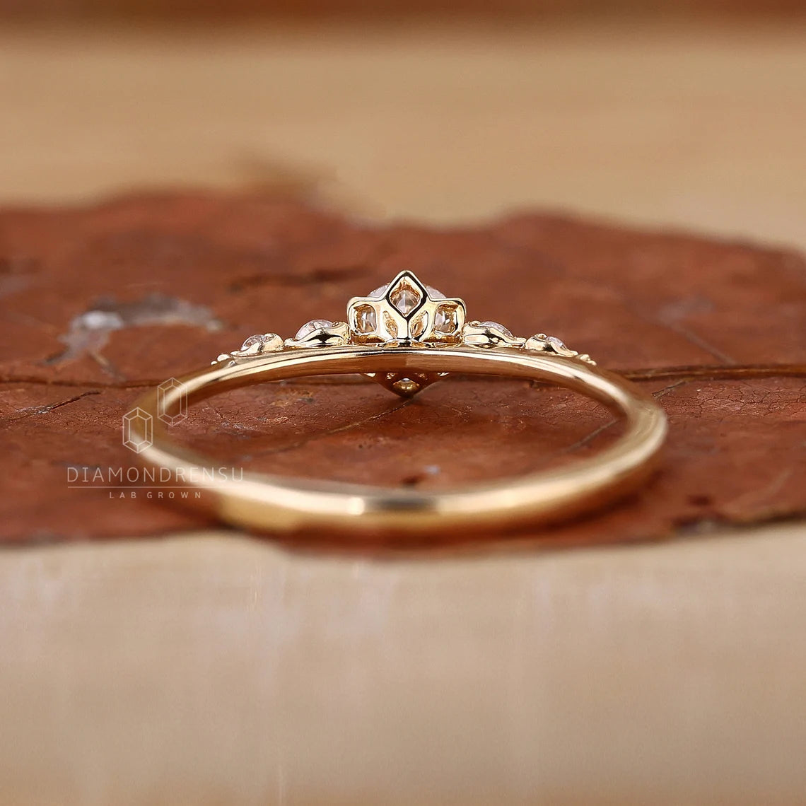 Gold ring with diamond-like gemstones on a brown textured surface