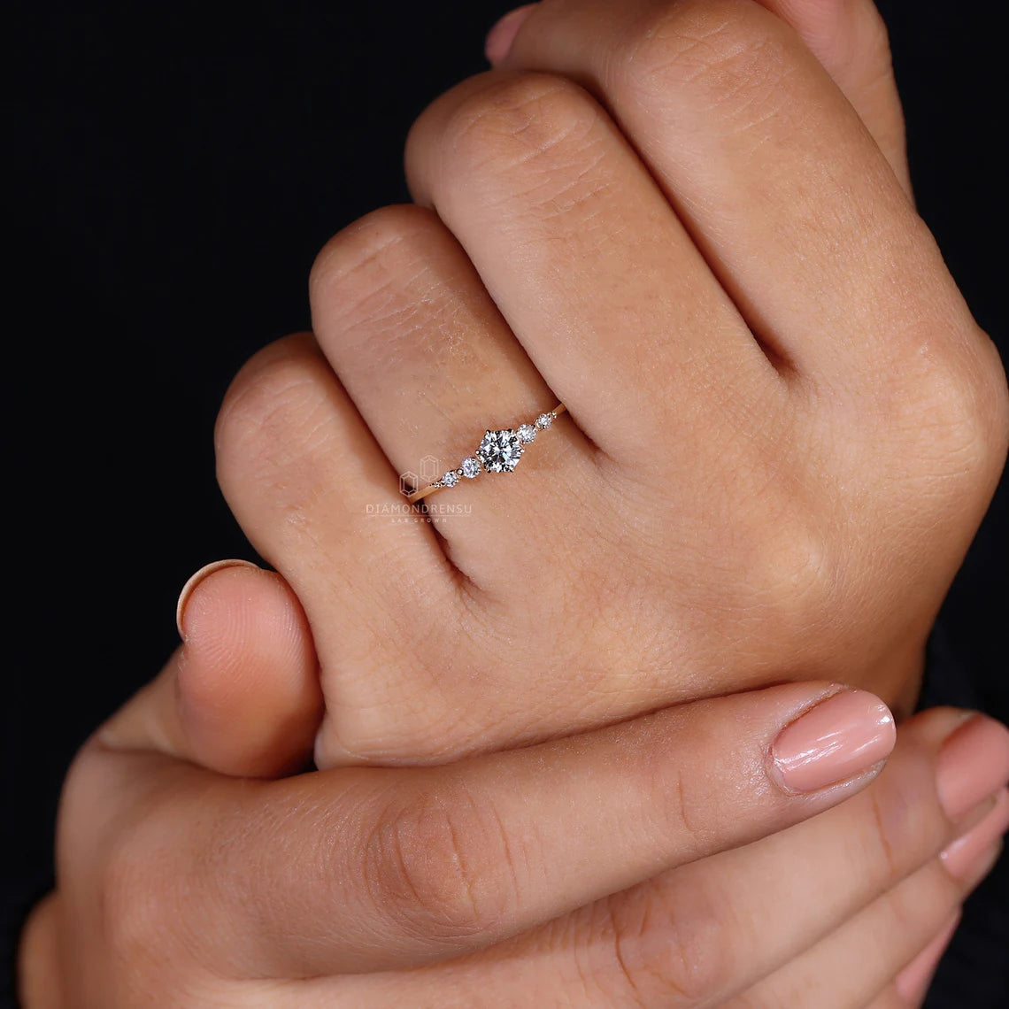 Close-up of a hand wearing a diamond ring on a black background