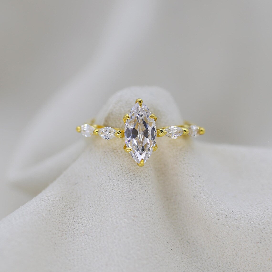 Gold ring with a large central diamond and smaller diamonds on a white background
