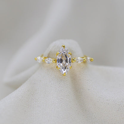 Gold ring with a large central diamond and smaller diamonds on a white background
