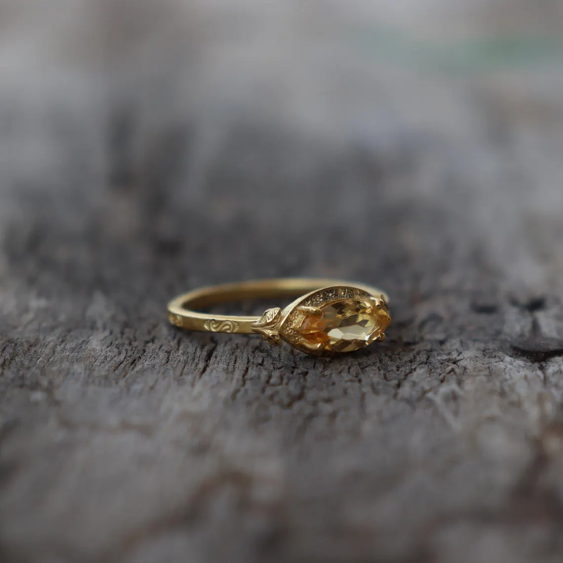 Gold ring with a yellow gemstone on a textured surface