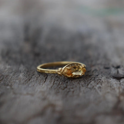 Gold ring with a yellow gemstone on a textured surface