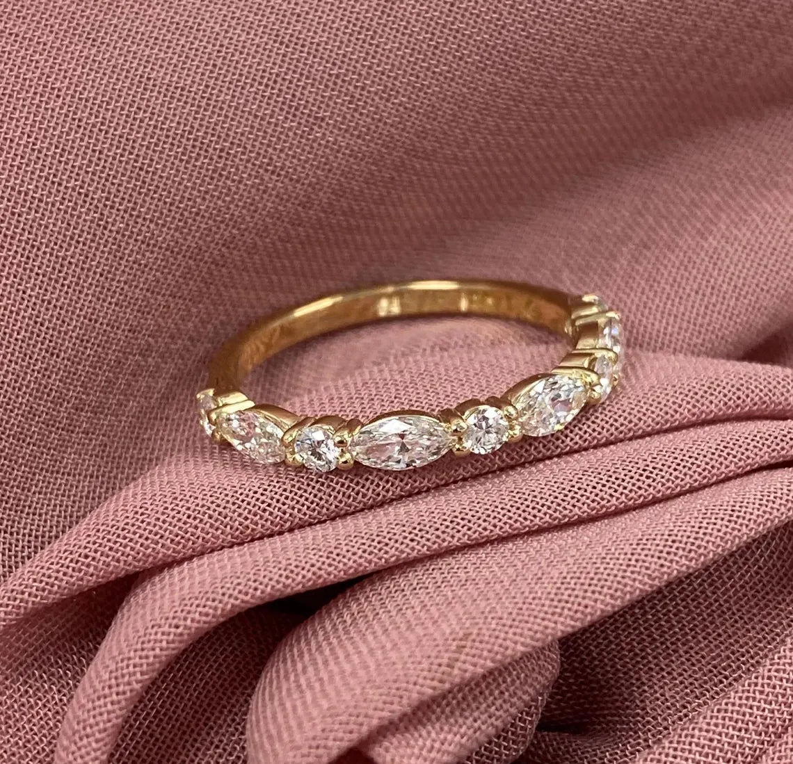 Gold ring with diamonds on a pink fabric background