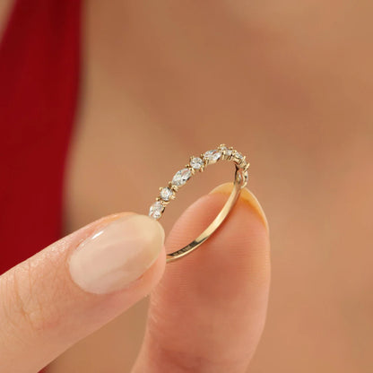 Gold ring with small diamonds held between fingers against a blurred background