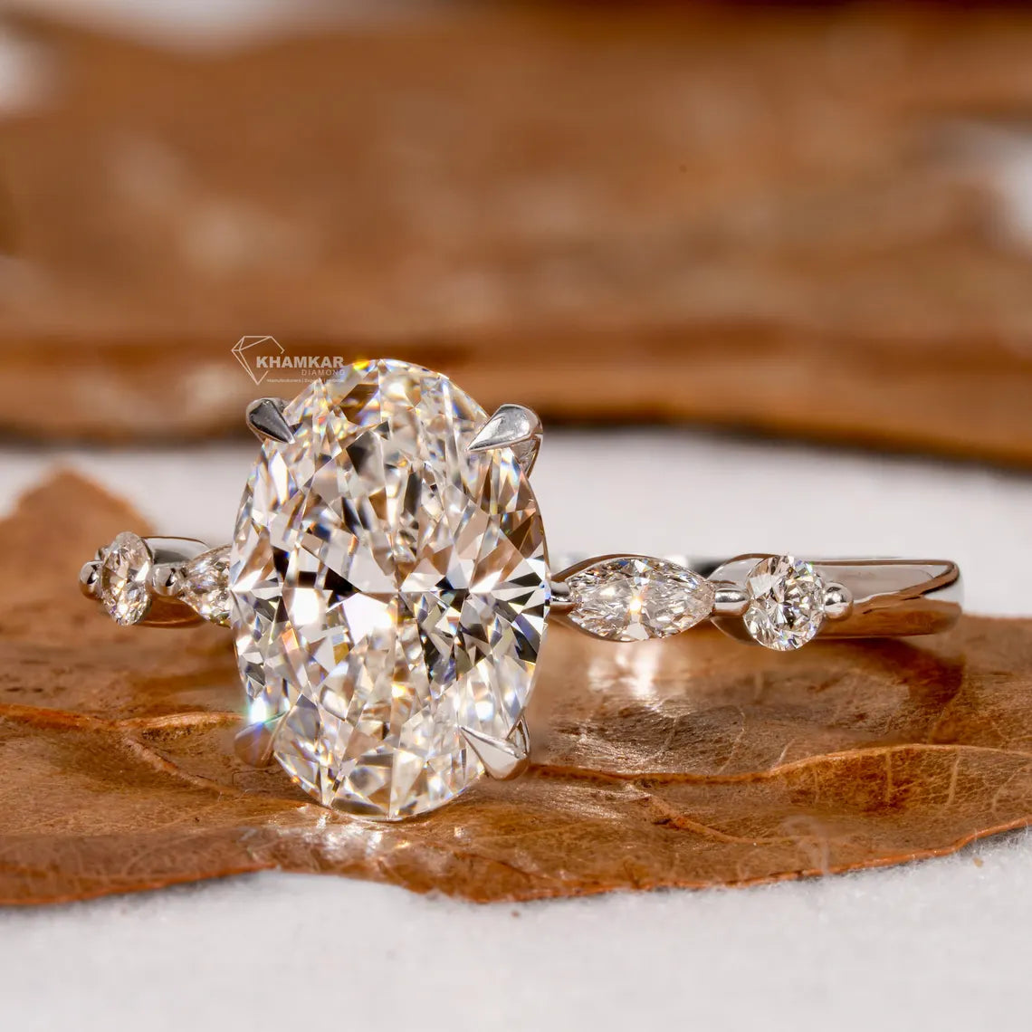 Diamond ring with a large central gemstone and smaller stones on a brown leaf