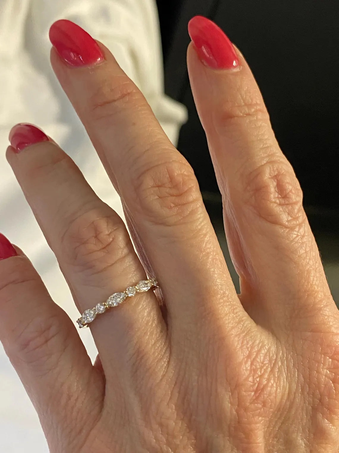 Close-up of a hand wearing a diamond ring with red nail polish.