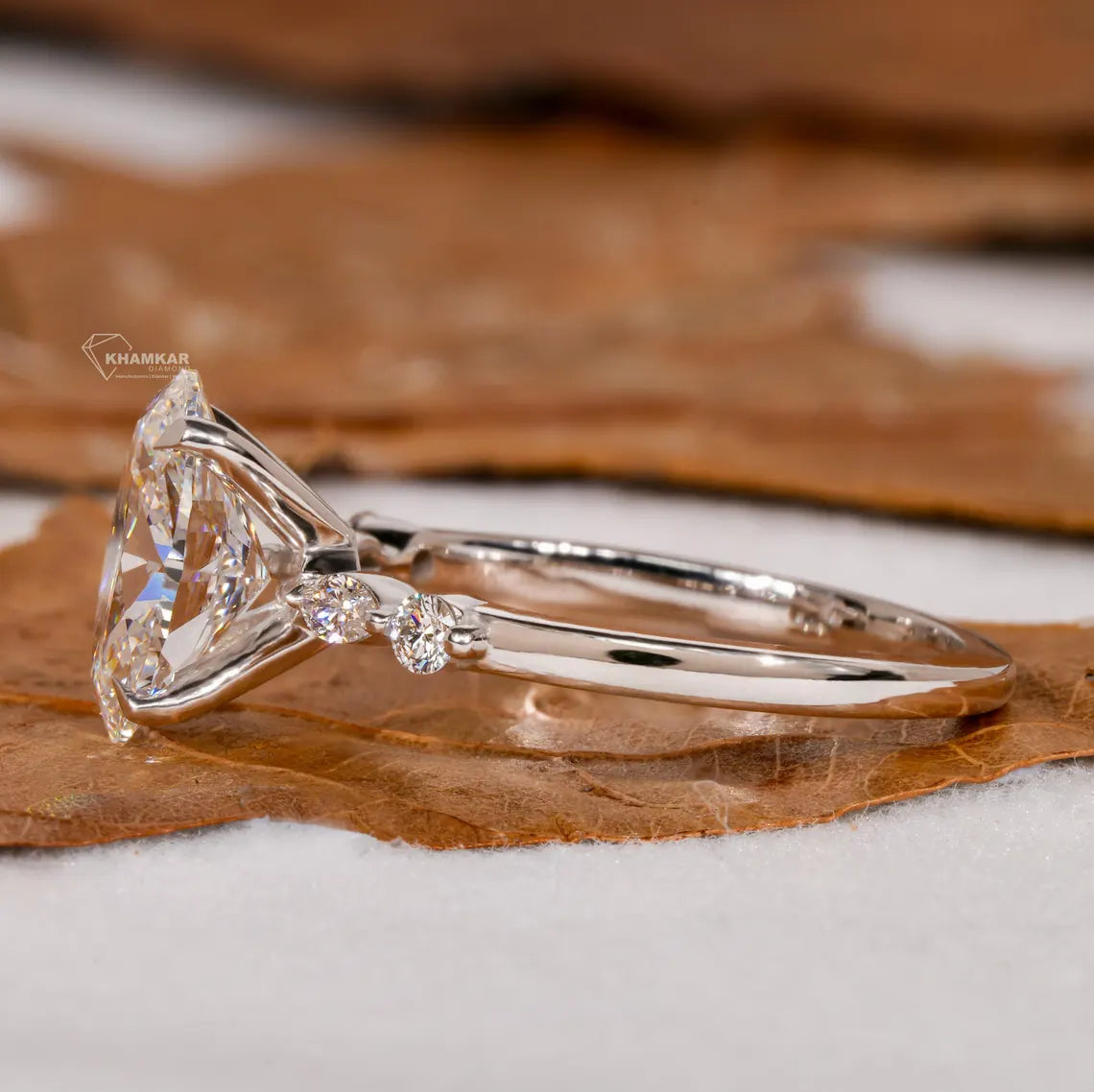 Diamond ring with a triangular cut stone on a brown leaf