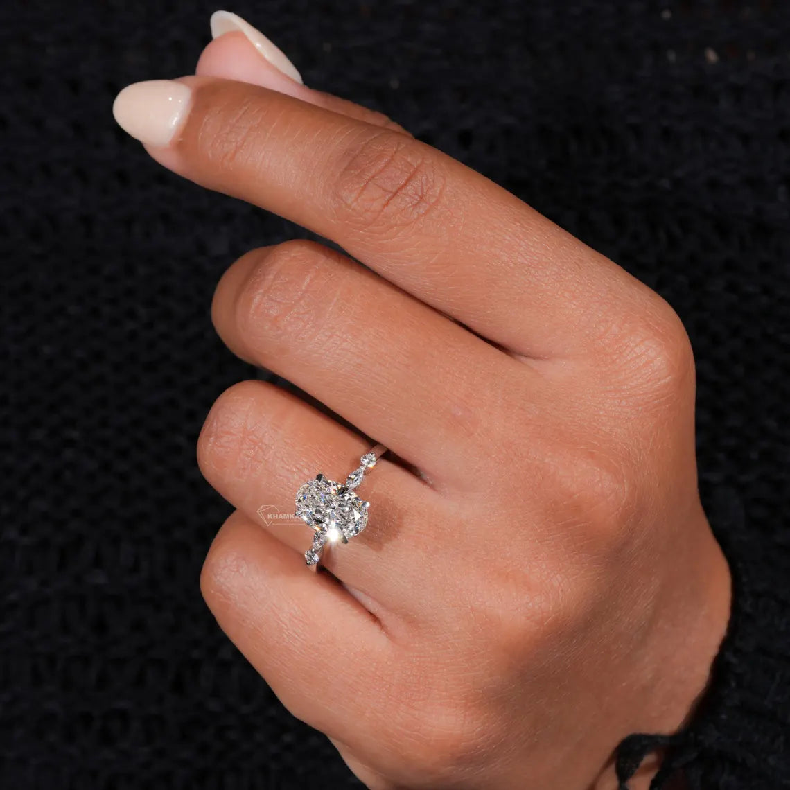 Close-up of a hand wearing a diamond ring on a black textured background