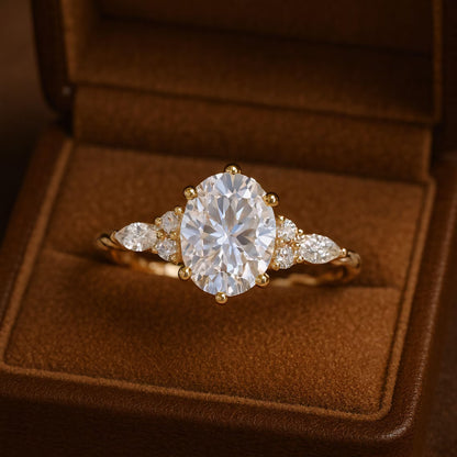 Gold ring with a large diamond and smaller diamonds on either side, displayed in an open brown jewelry box.