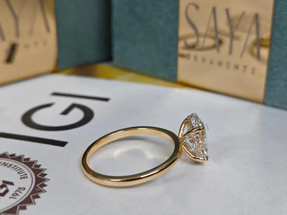 Gold ring with a diamond on a white surface with 'Saya' branding in the background.