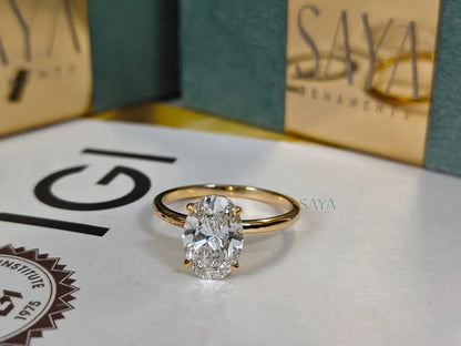Gold ring with a diamond on a surface with 'Saya' and 'IGI' logos in the background.
