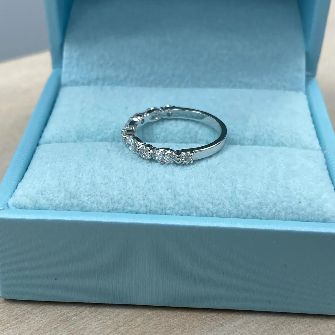 Silver ring with gemstones in a blue jewelry box