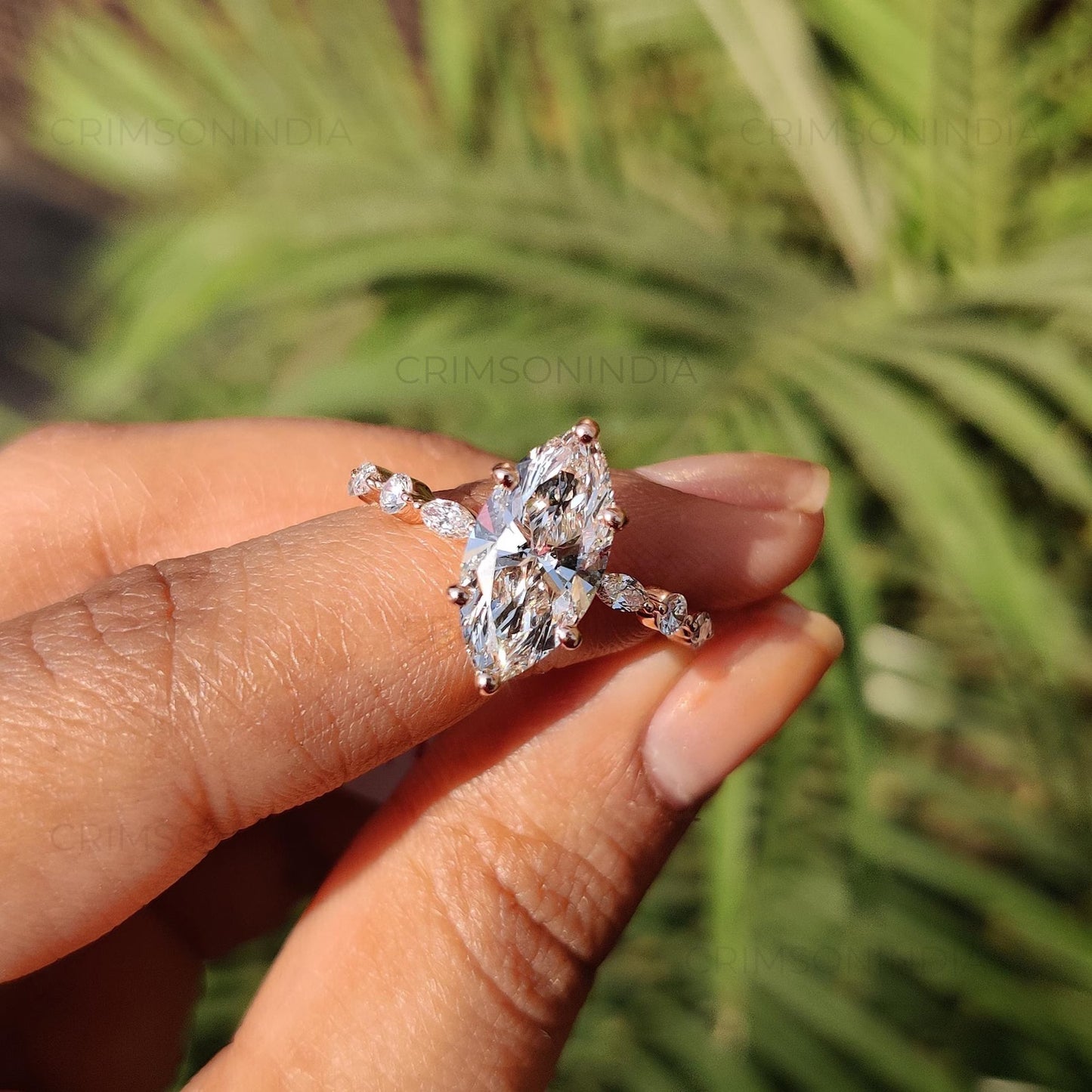 Diamond ring held between fingers with a blurred green background