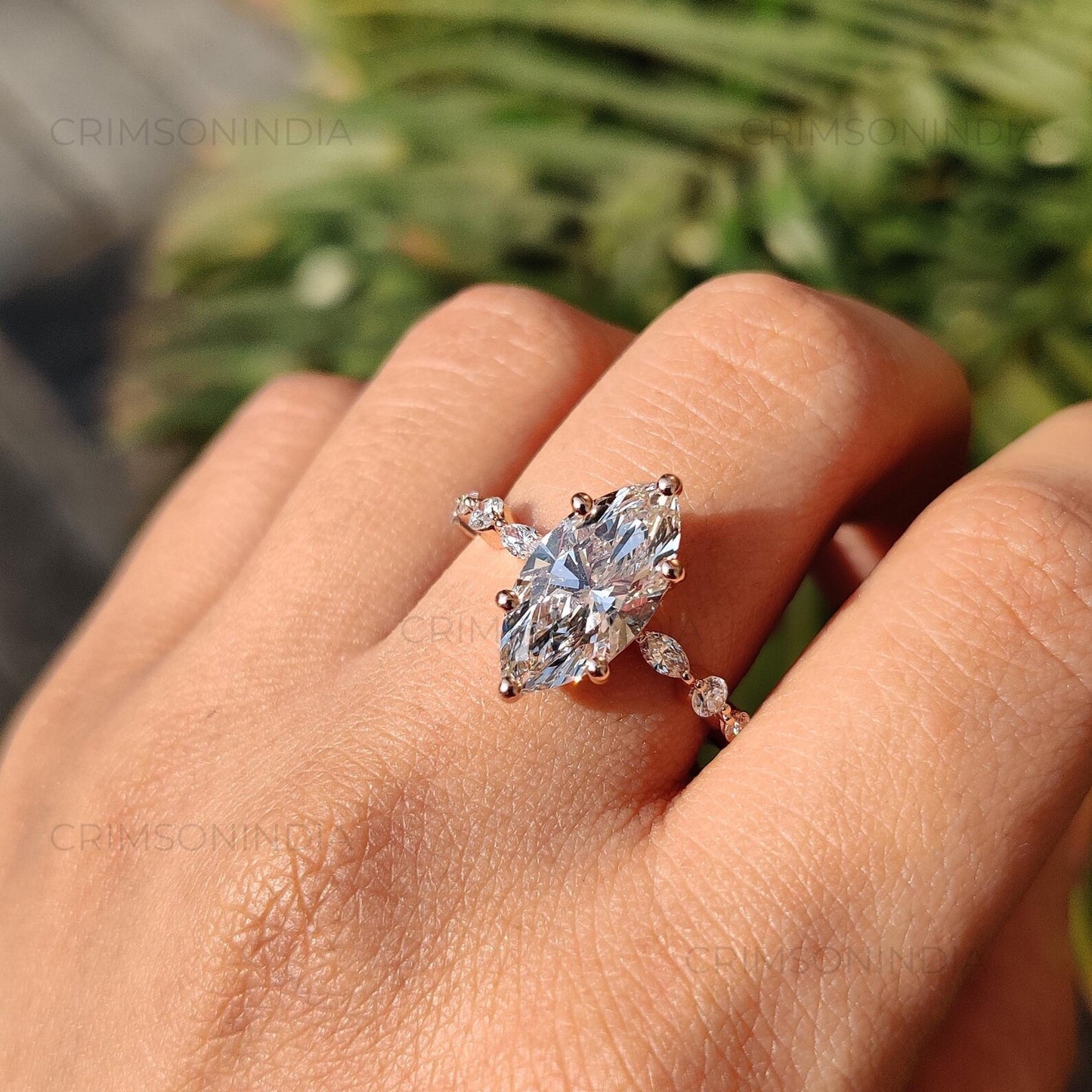 Rose gold ring with a large diamond on a hand against a blurred green background